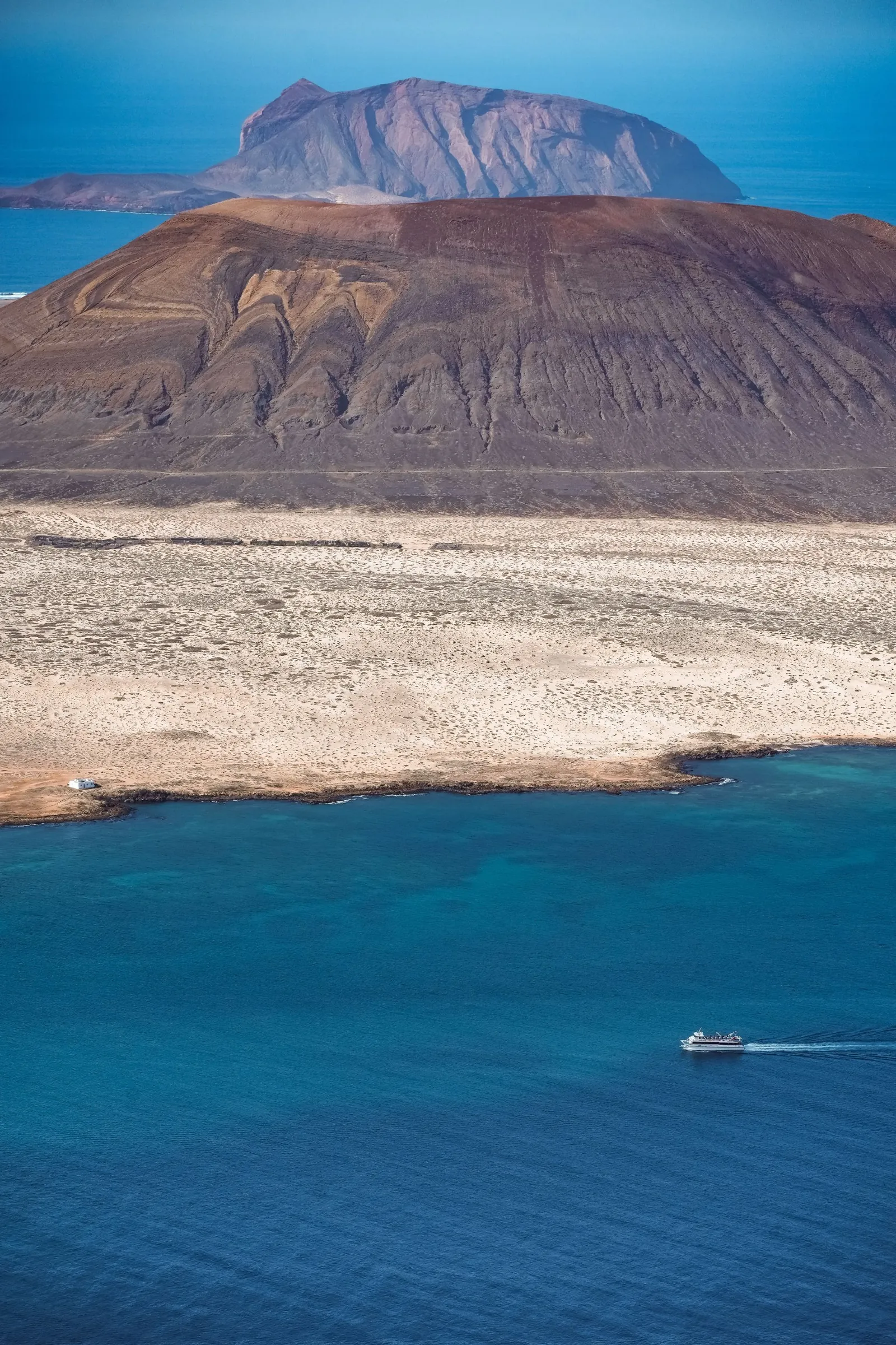 A small ferry crossing the blue strait towards La Graciosa