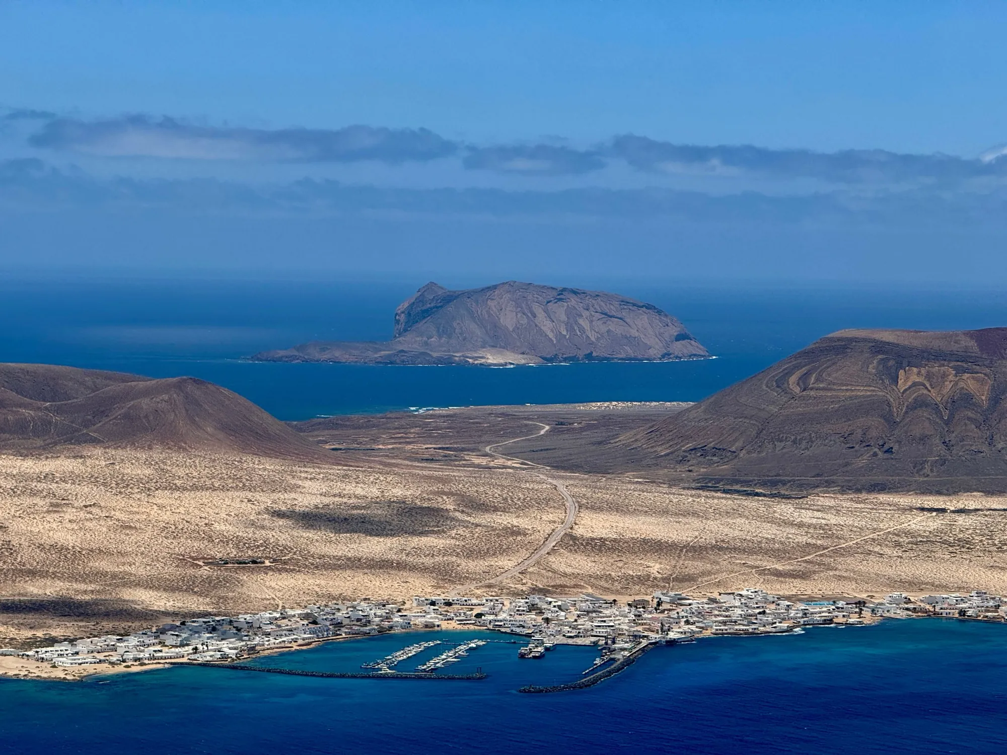 Caleta de Sebo and its harbour below sandy plains and volcanoes